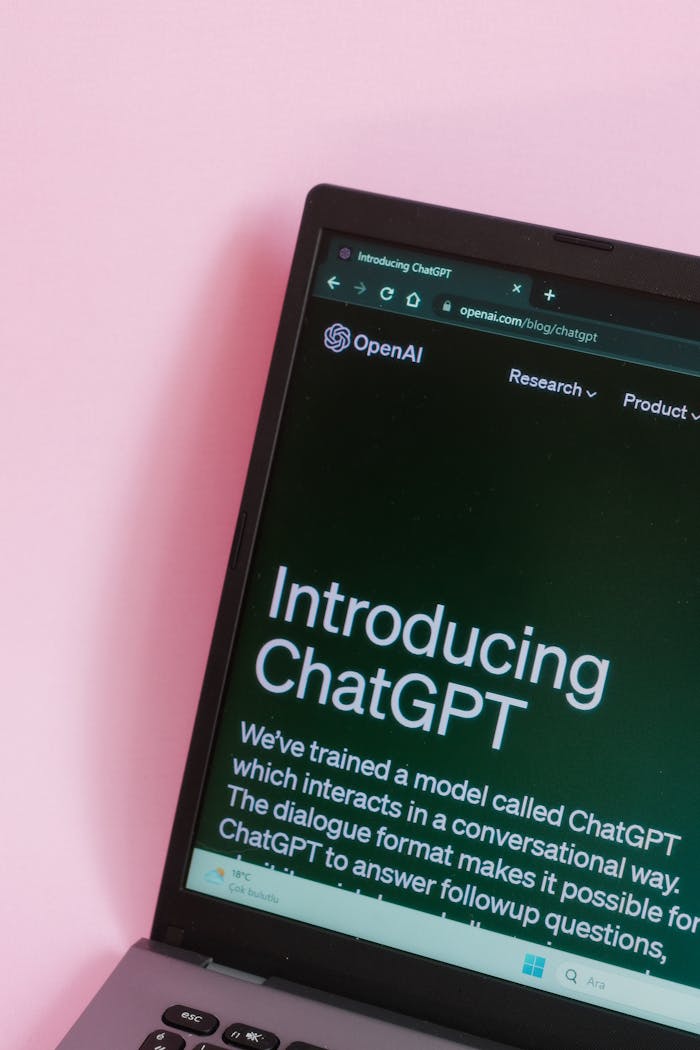 who-we-are Close-up of a laptop with ChatGPT introduction on screen against a pink background.